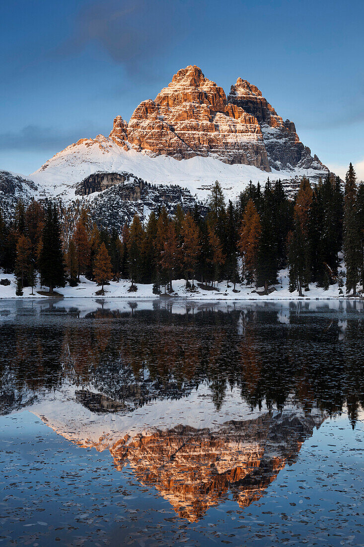 Blick von Süd-Westen auf die eindrucksvoll erleuchteten Drei Zinnen mit ihrer Spiegelung im Lago de Antorno, Südtirol, Italien