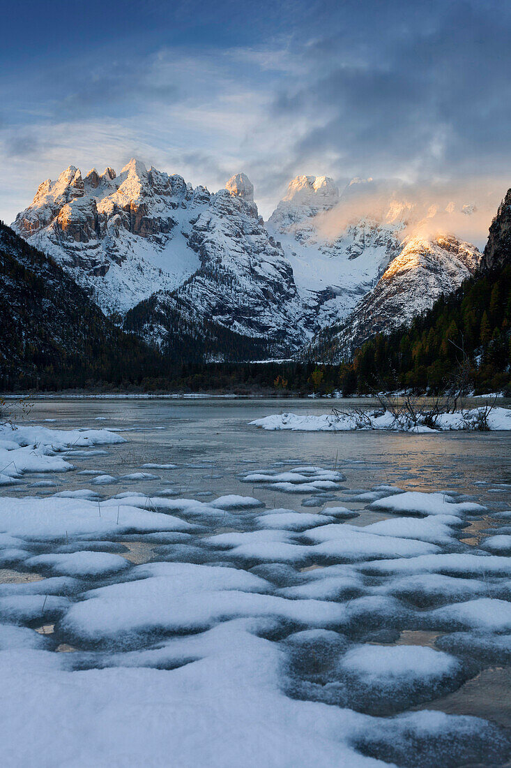 Frostiger Sonnenaufgang über dem gefrorenen Dürrensee mit Blick auf den M. Cristallo, nach ersten Schneefällen in den Dolomiten Mitte Oktober, Belluno, Südtirol, Italien