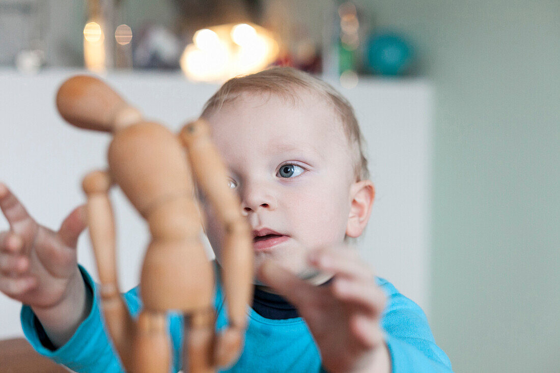 Boy (2 years) playing with a wooden mannequin, Leipzig, Saxony, Germany