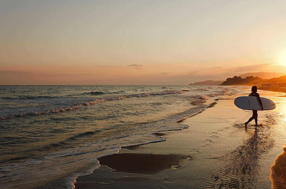 Surfer walking along the beach in the sunset, Castiglione della Pescaia, Mediterranean Sea, province of Grosseto, Tuscany, Italy, Europe