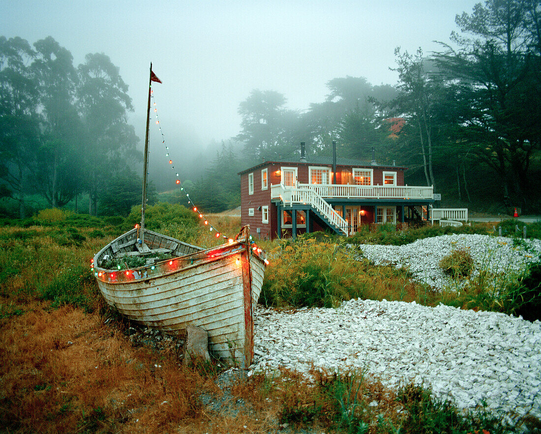 USA, California, Tomales Bay, a fishing boat, a cottage and thousands of oyster shells at Nick's Cove, Marshall