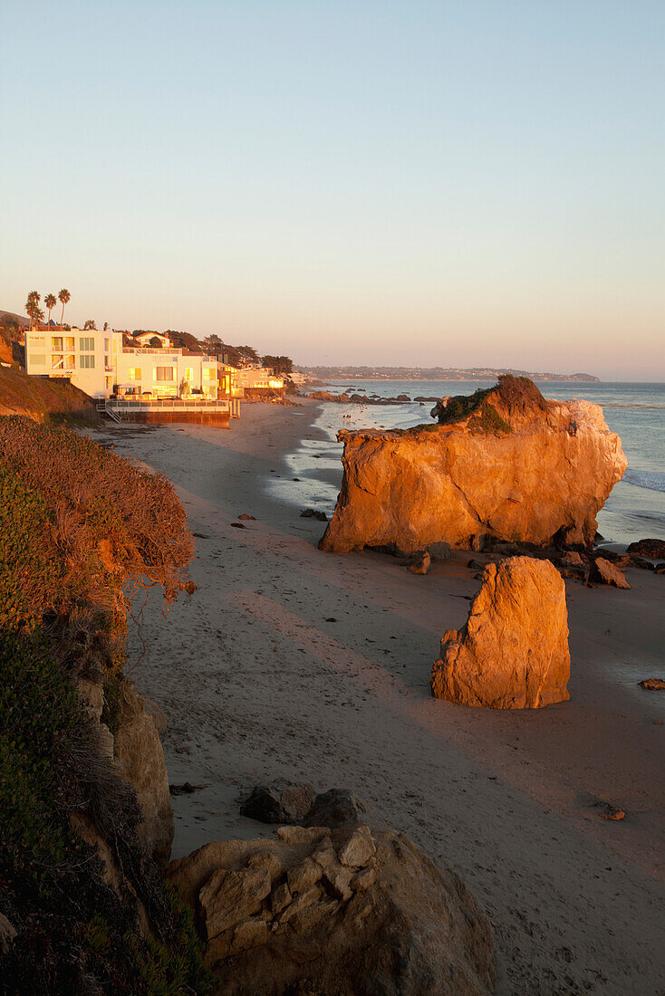 USA, California, Malibu, El Matador beach at sunset, large rock formations with Malibu beach homes in the distance