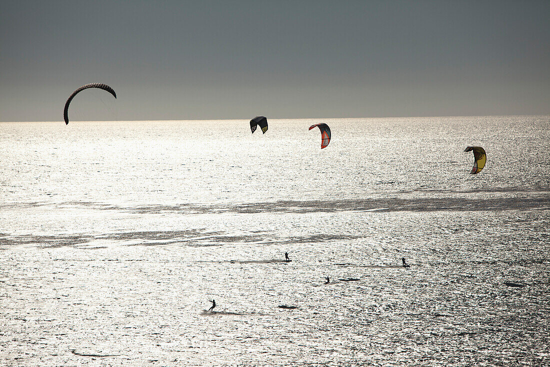 USA, California, Malibu, kite surfers play in the Pacific off of Broad Beach
