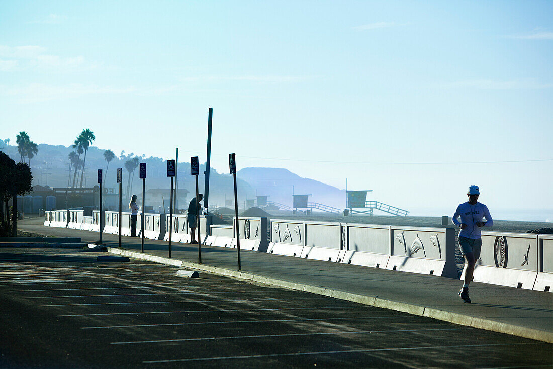 USA, California, Malibu, a man jogs along Zuma Beach in the early morning