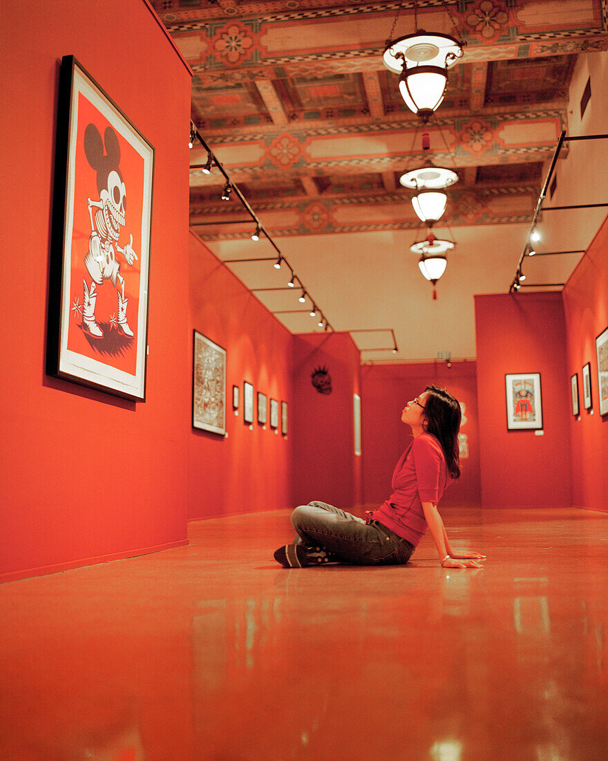 USA, California, Santa Monica, a young woman sits and admires artwork at an exhibit at the Santa Monica Public Library