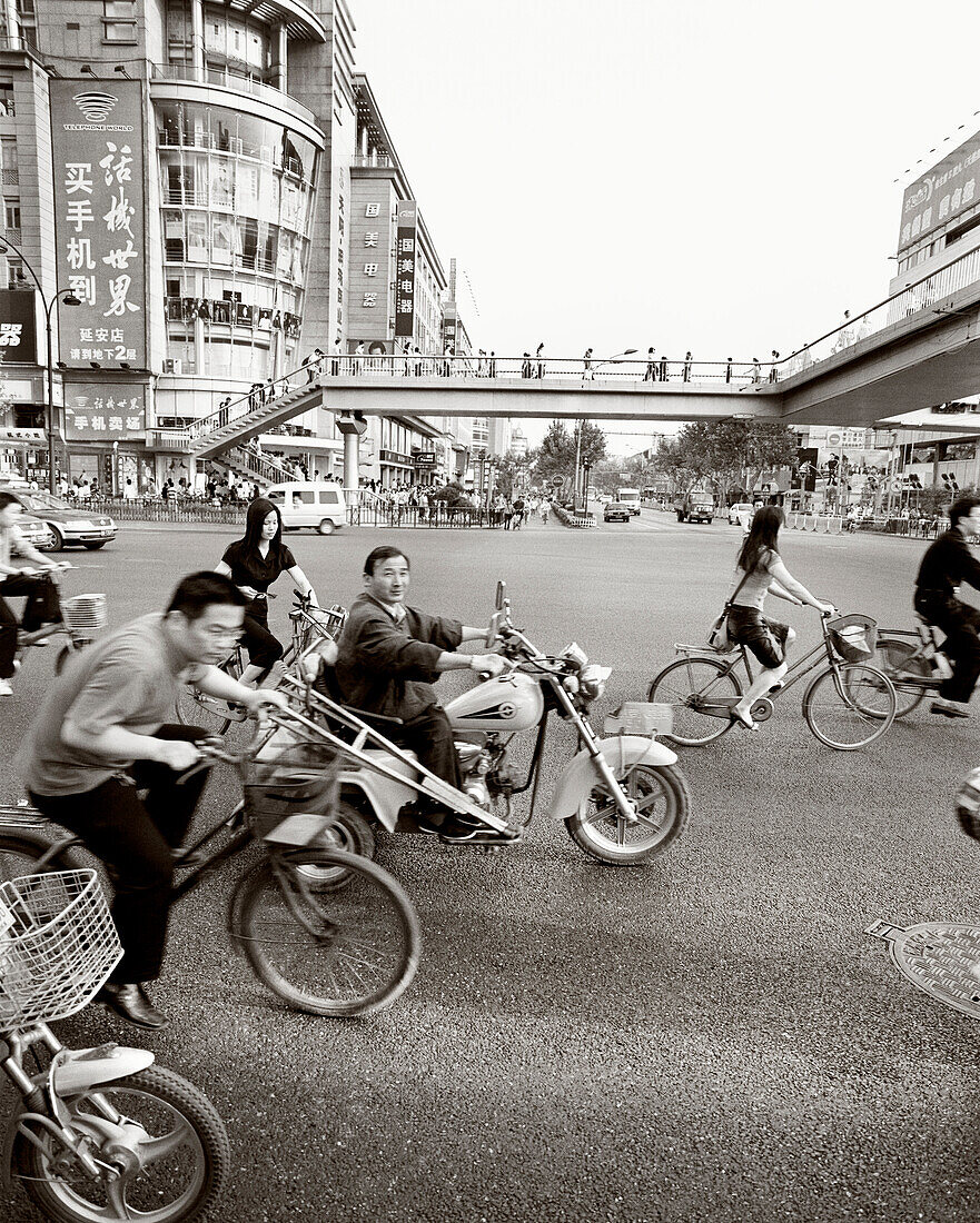 CHINA, Hangzhou, people riding bicycles and motorcycles in an urban area (B&W)