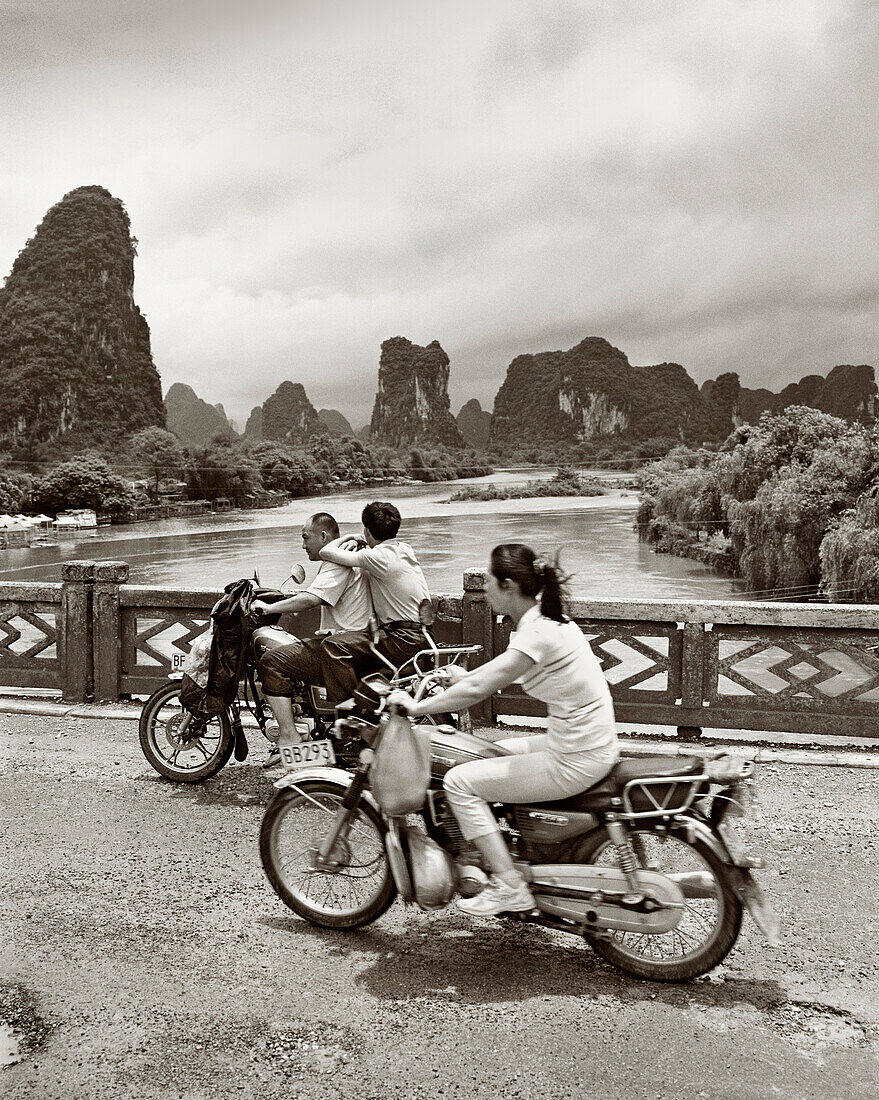 CHINA, Guilin, people traveling in motorcycles over bridge in rural Guilin (B&W)