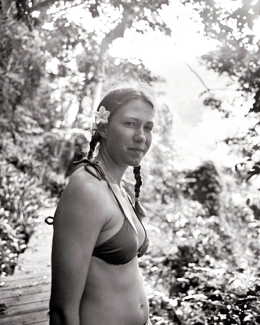 FIJI, Northern Lau Islands, a young woman stands on a path cut through a lush jungle (B&W)