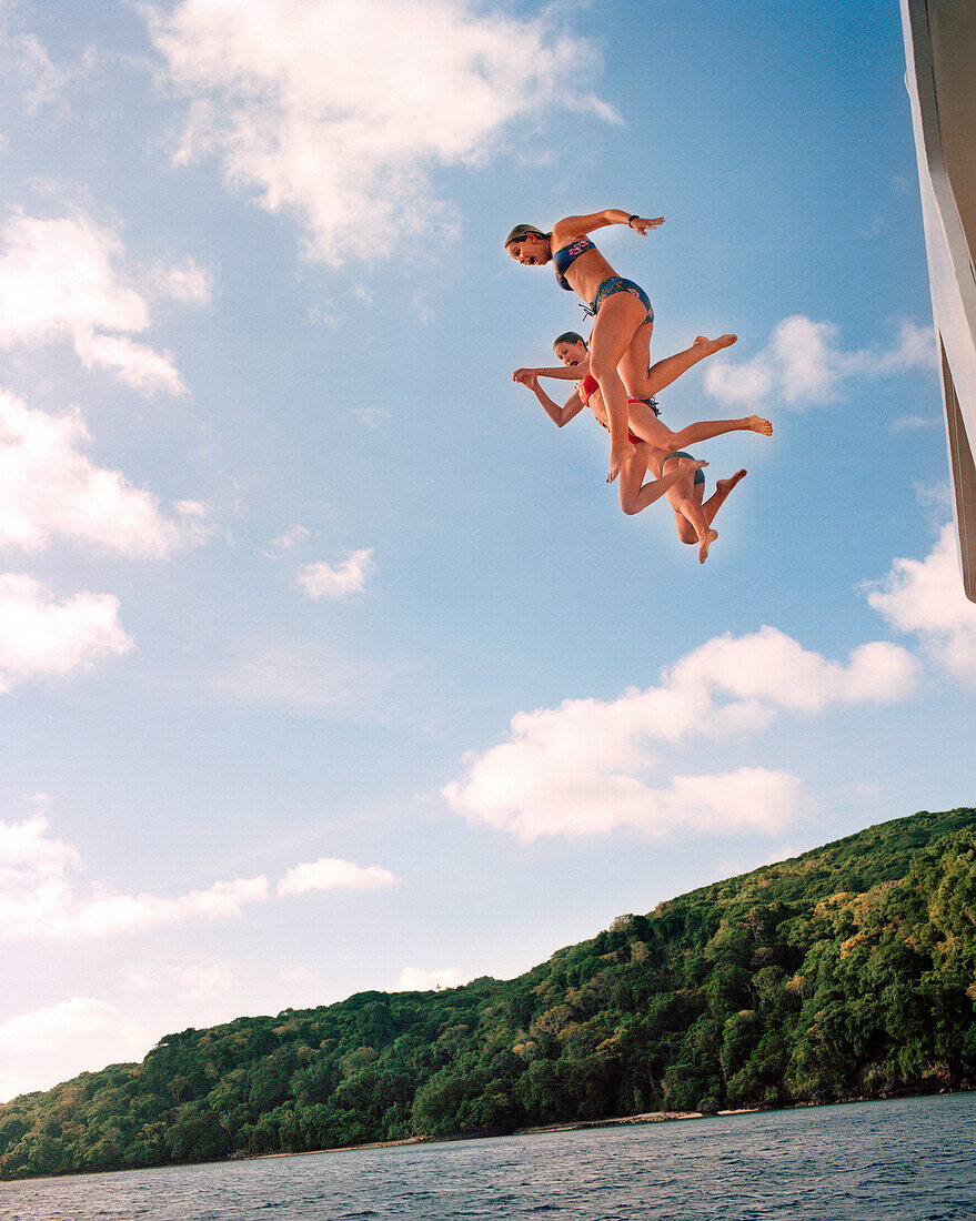 FIJI, Northern Lau Islands, young women jump off the top of a yacht into the South Pacific Ocean