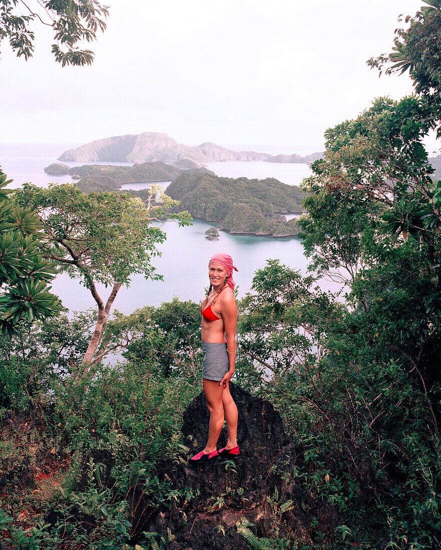 FIJI, Northern Lau Islands, a young woman stands on top of a lush uninhabited jungle island