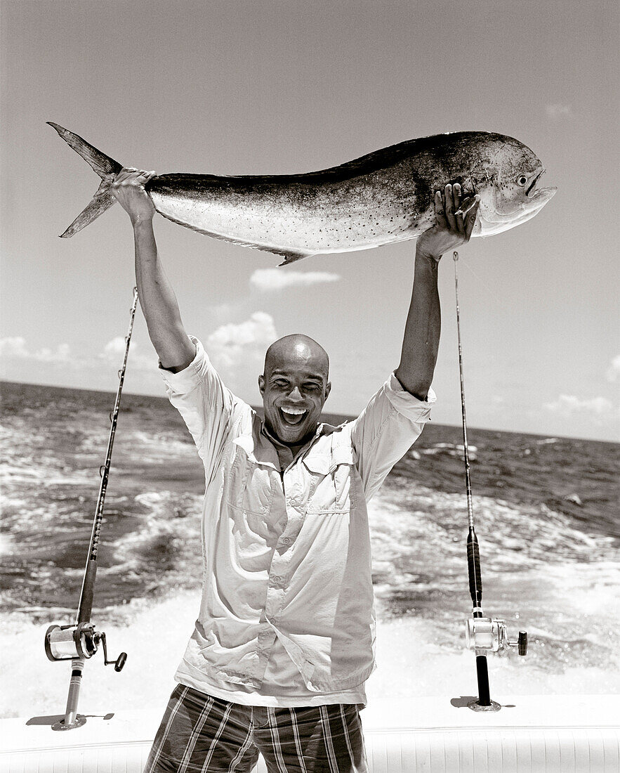 USA, Florida, man on boat holding up the catch of the day, Mahi Mahi, Islamorada (B&W)