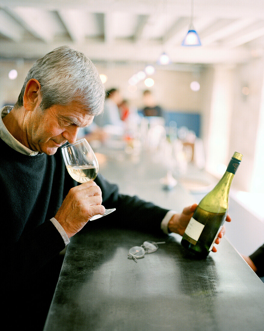 FRANCE, Chablis, Burgundy, the owner Michael Laroche smelling wine at the bar, Laroche Restaurant