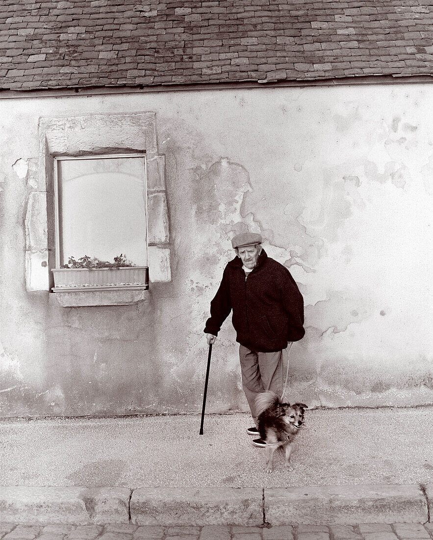 FRANCE, Burgundy (B&W), senior man standing with a pet dog, Chablis