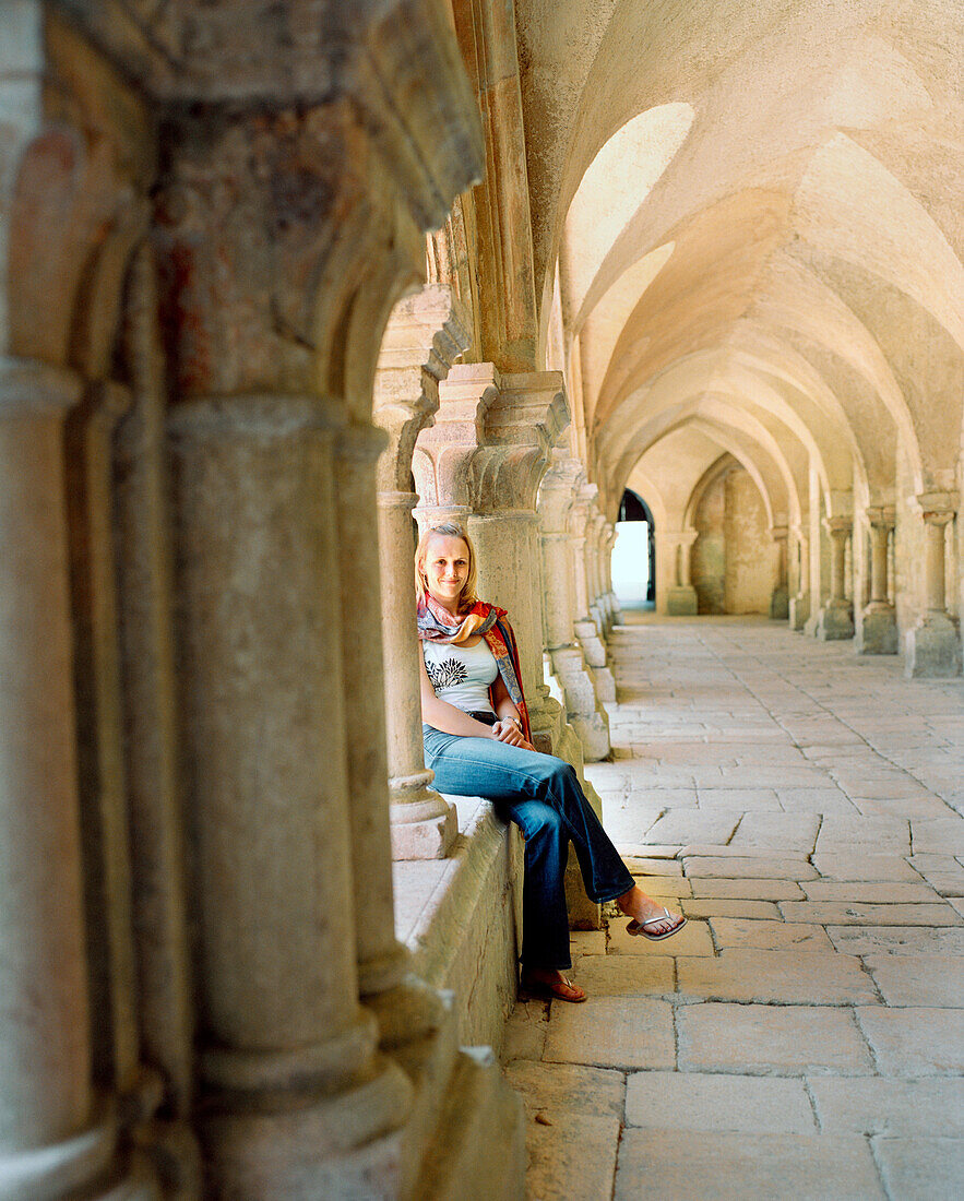FRANCE, Burgundy, young woman sitting in Abbaye De Fontenay, Marmagne