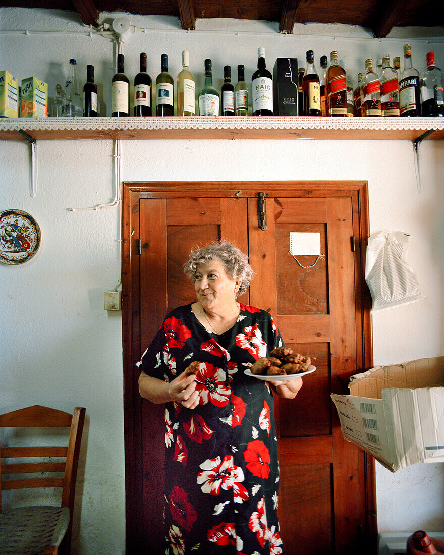 GREECE, Patmos, Diakofti, Dodecanese Island, Katerina Grillakis holds a plate of fried zucchini balls in the kitchen at her Diakofti Taverna