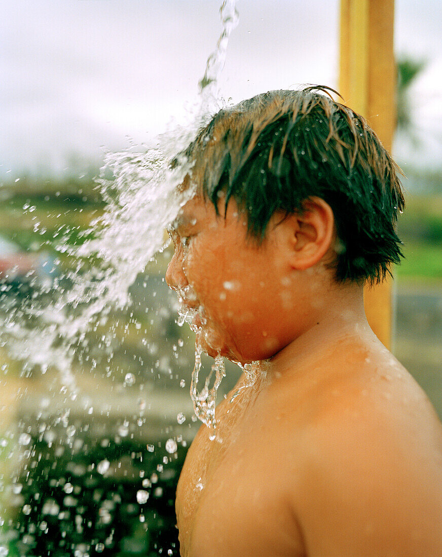 USA, Hawaii, The Big Island, close-up of a young boy under an outdoor shower