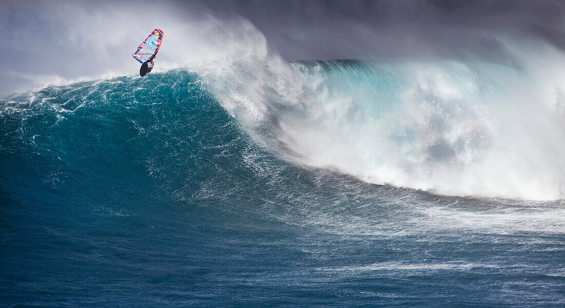 USA, Hawaii, Maui, a man windsurfs and gets air on a huge wave at a break called Jaws or Peahi