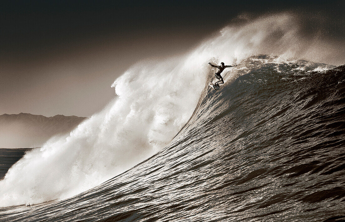 USA, Hawaii, man surfs a large wave on an outer reef, the North Shore of Oahu (B&W)