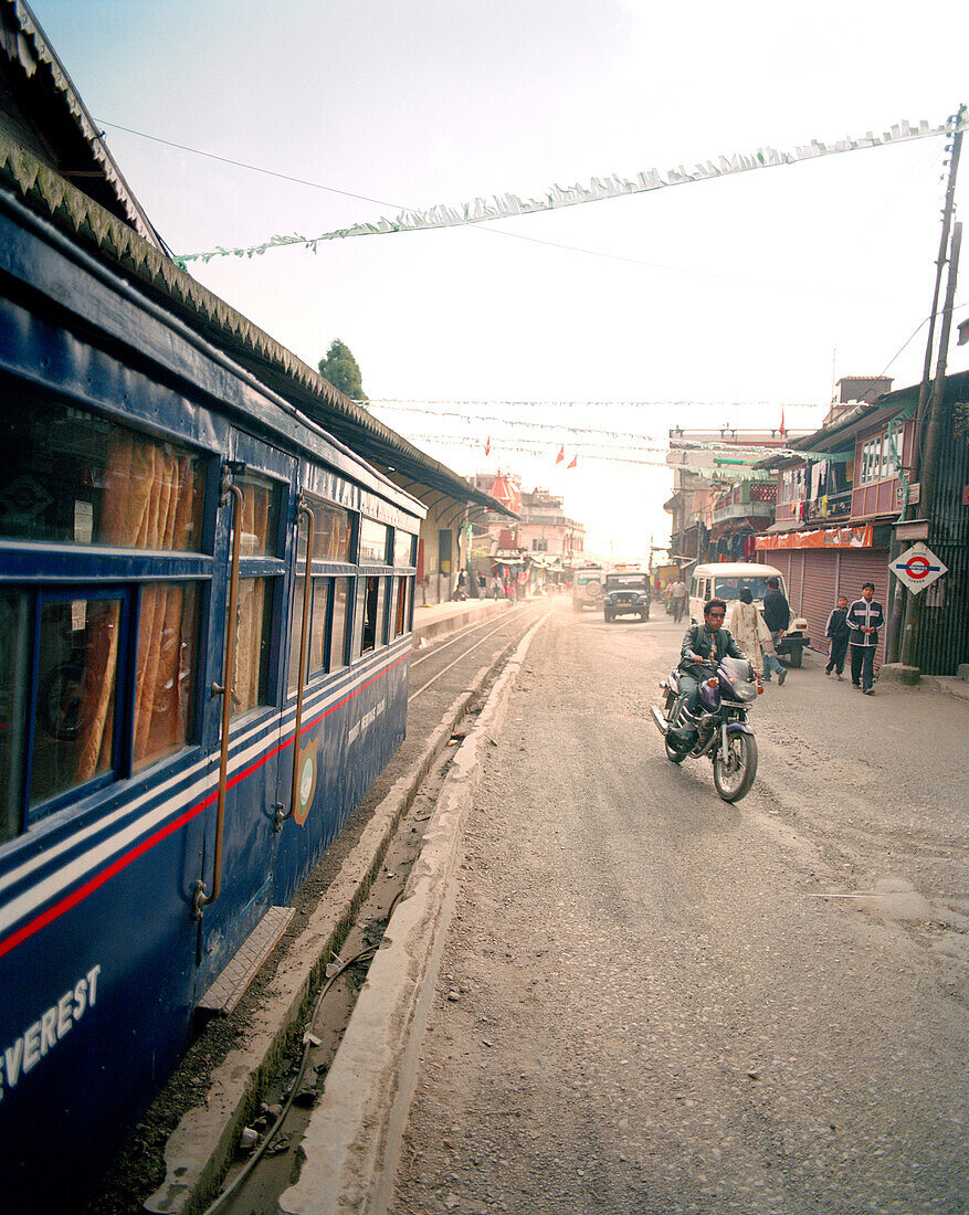 INDIA, West Bengal, man riding motorcycle by train, Darjeeling