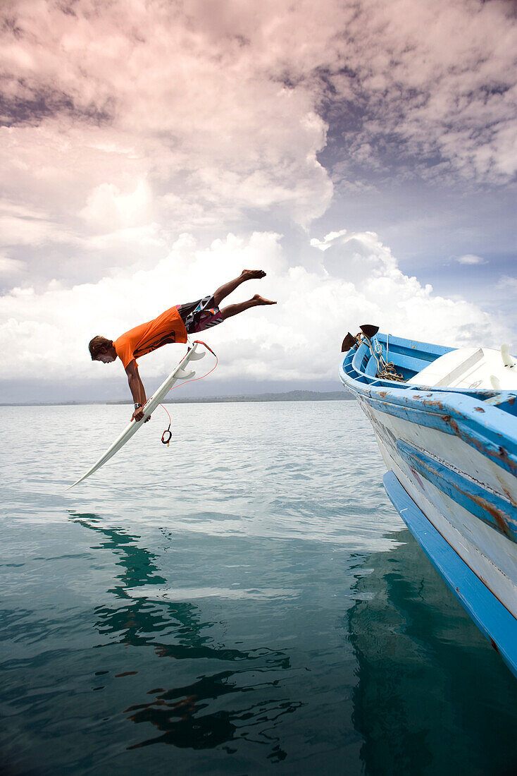 INDONESIA, Mentawai Islands, Kandui Surf Resort, surfer diving into the Indian Ocean with his surfboard