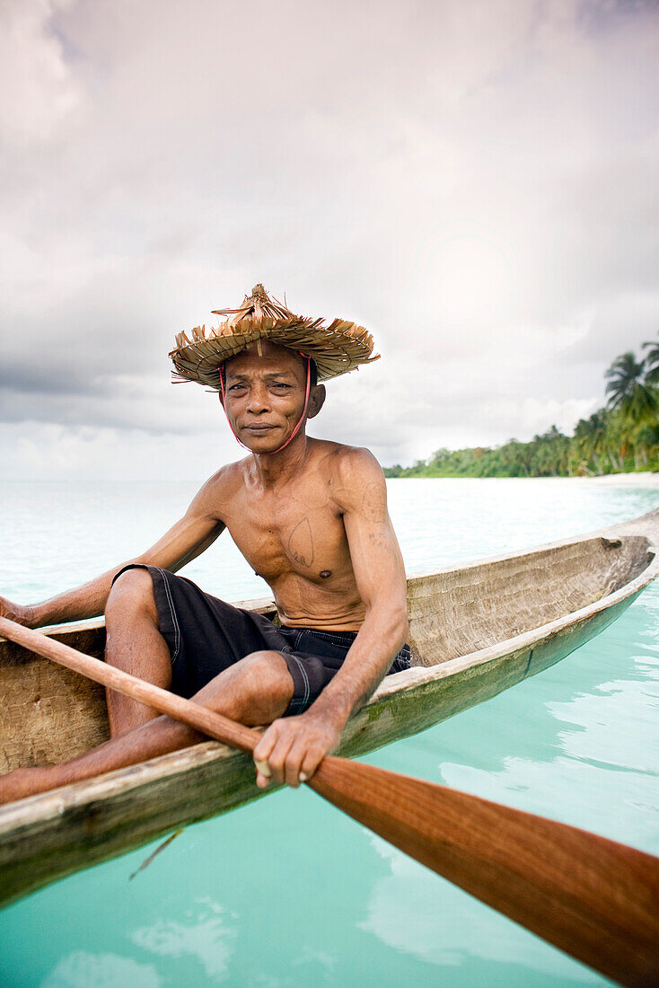 INDONESIA, Mentawai Islands, Kandui Resort, fisherman Gesayas Ges paddling his dugout canoe