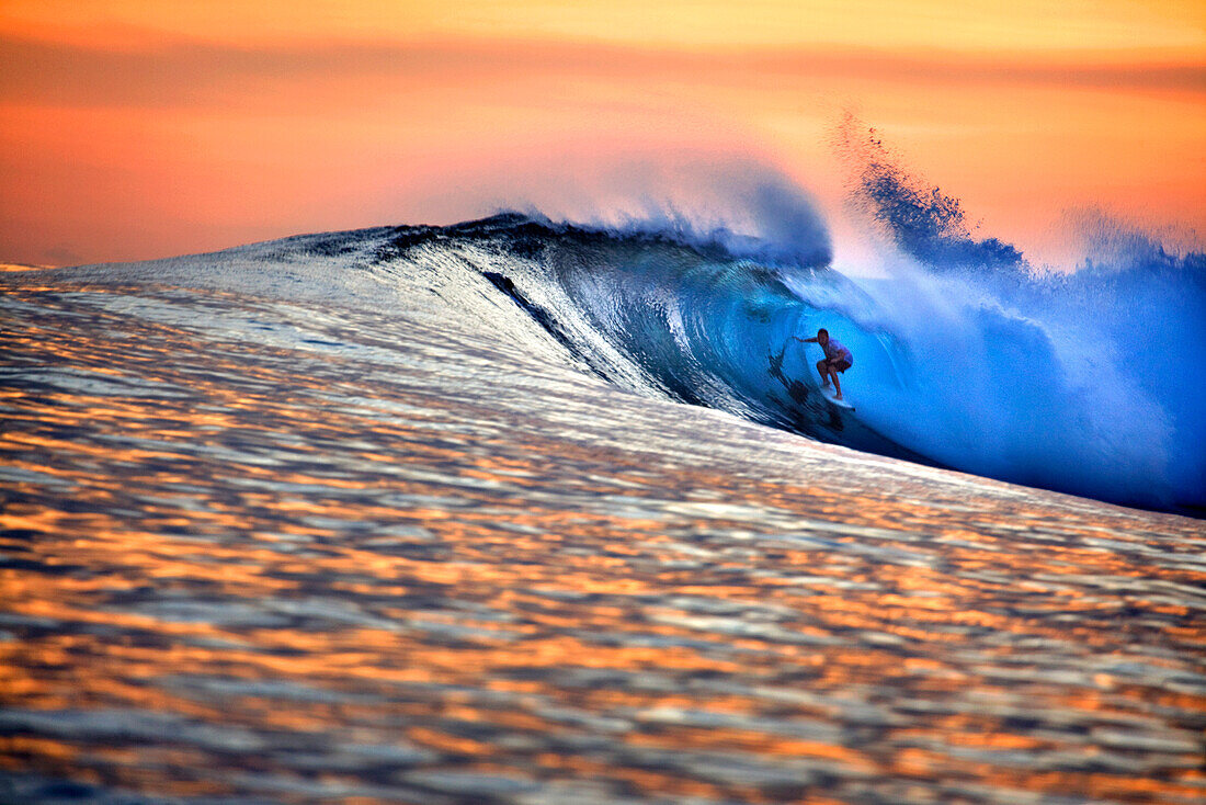 INDONESIA, Mentawai Islands, Kandui Resort, man surfing on wave at dusk, Bankvaults