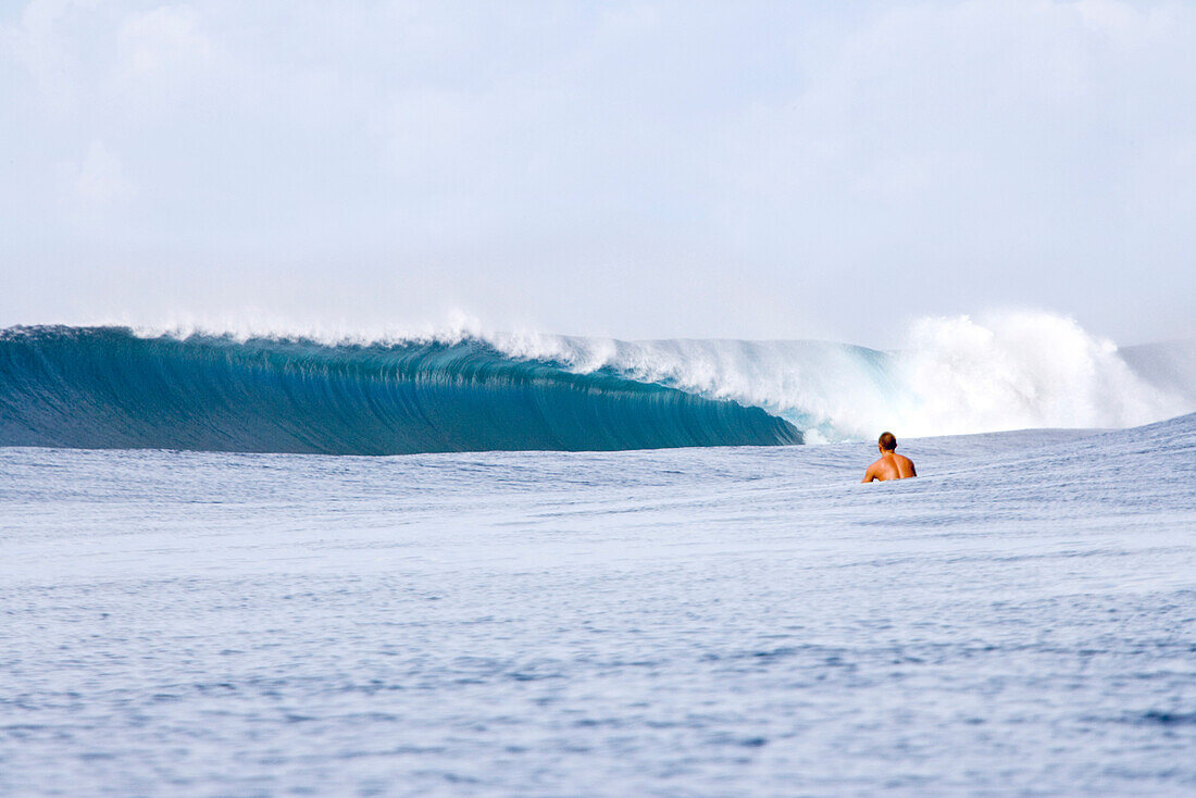 INDONESIA, Mentawai Islands, Kandui Resort, a lone surfer watching a large wave break at Bankvaults