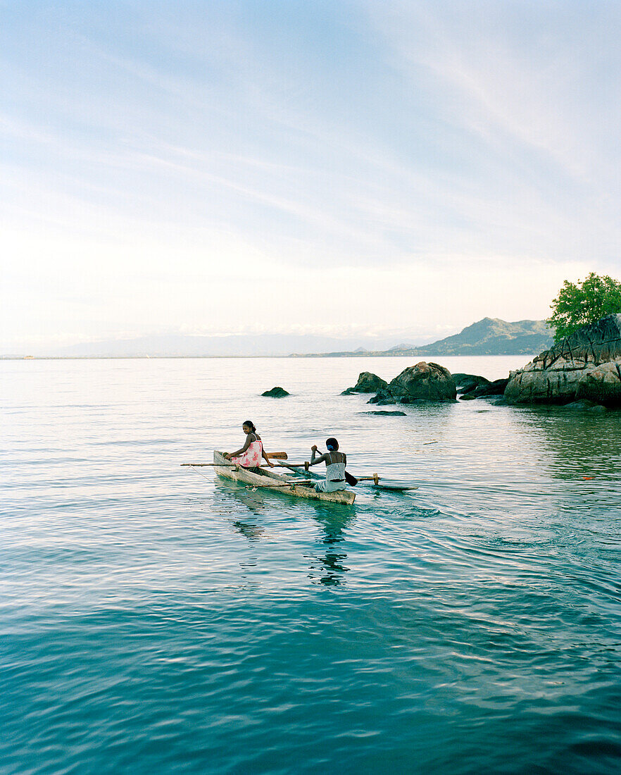 MADAGASCAR, two women traveling in a dugout canoe, Nosy Komba