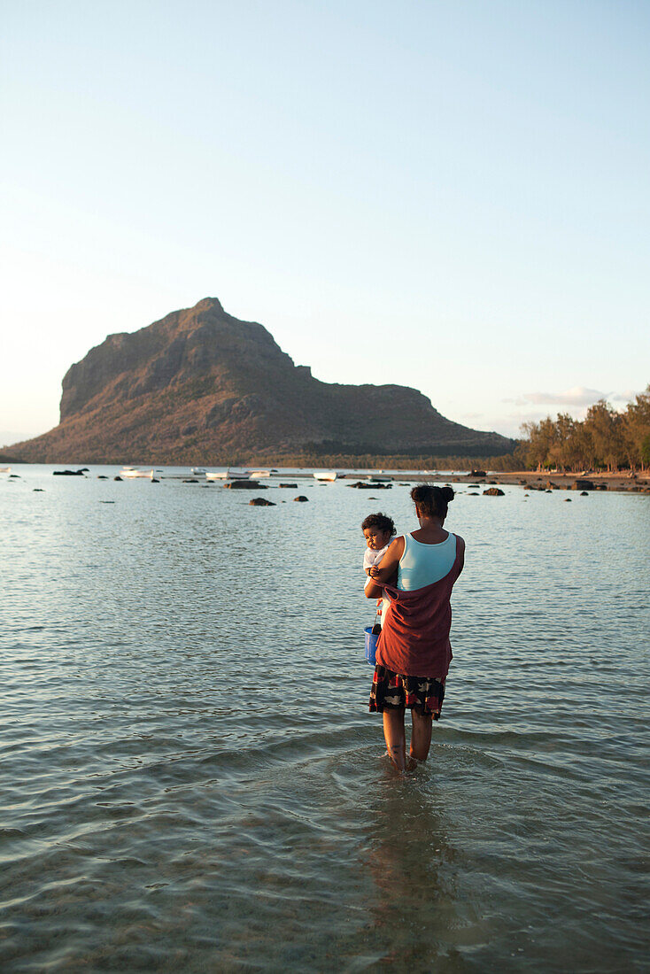 MAURITIUS, a mother and her child hunt for snails at low tide, Baie du Cap