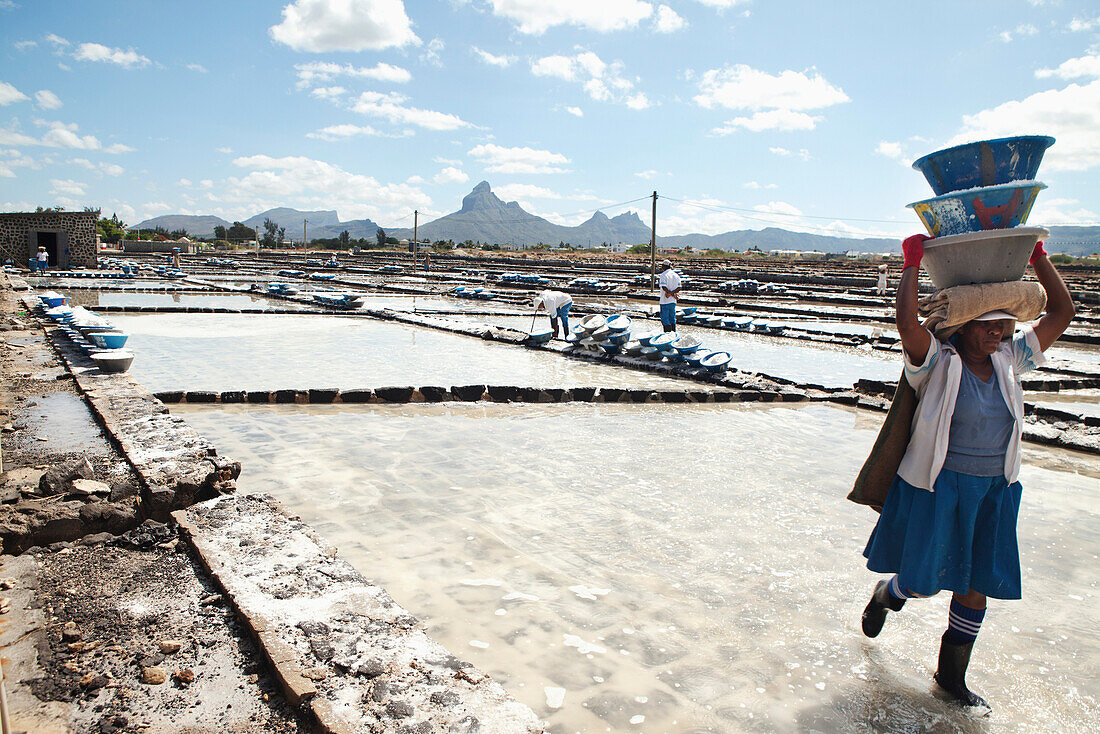 MAURITIUS, Tamarin, women carry heavy loads of salt to a storage facility where it is stored and prepared for transportation, Tamarin Salt Pans