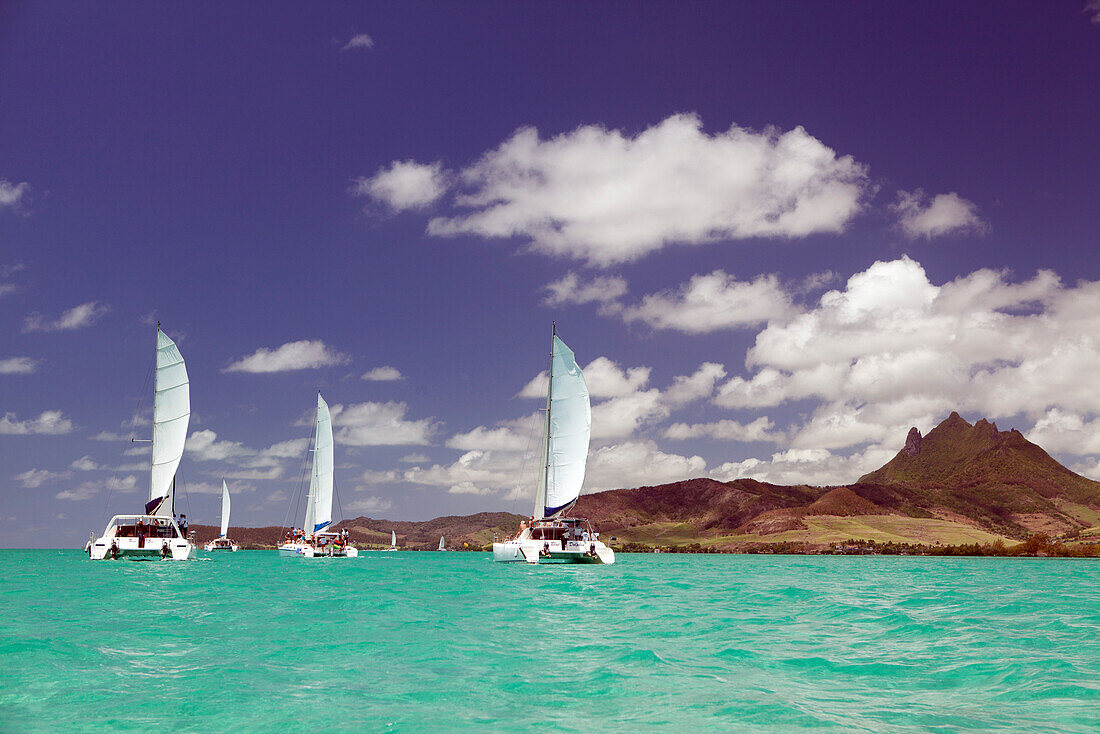 MAURITIUS, Trou D'eau Deuce, tourists sail in the Indian Ocean off the East coast of Mauritius with the 4 Sisters Mountains in the background