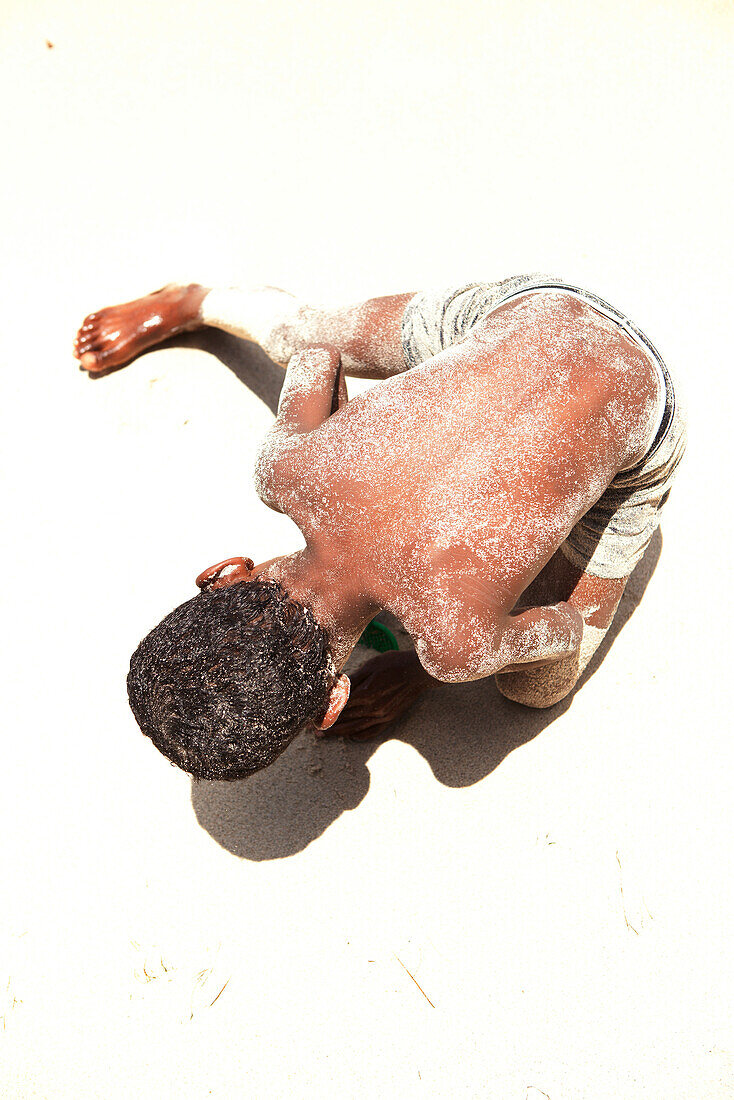 MAURITIUS, a boy plays in the sand on the beach at Ile aux Cerfs Island