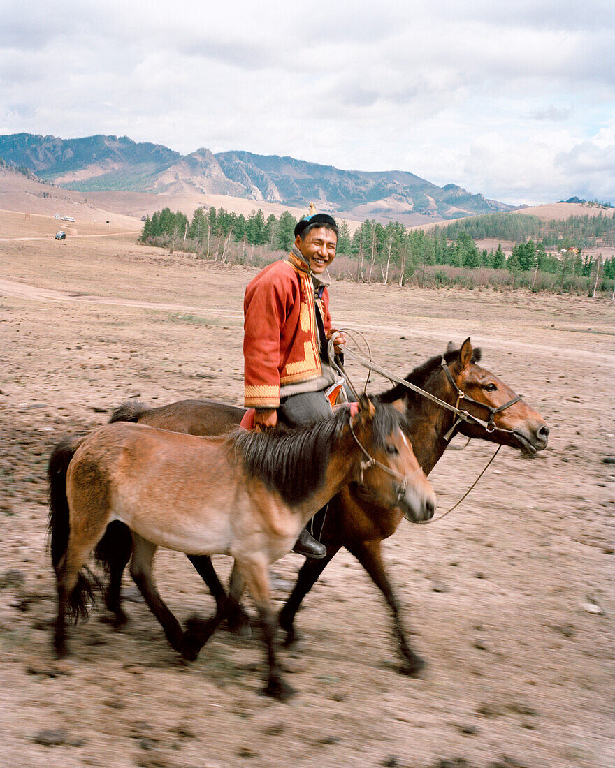 MONGOLIA, Gorkhi-Terelj National Park, a man on horseback leads a horse to his farm and home