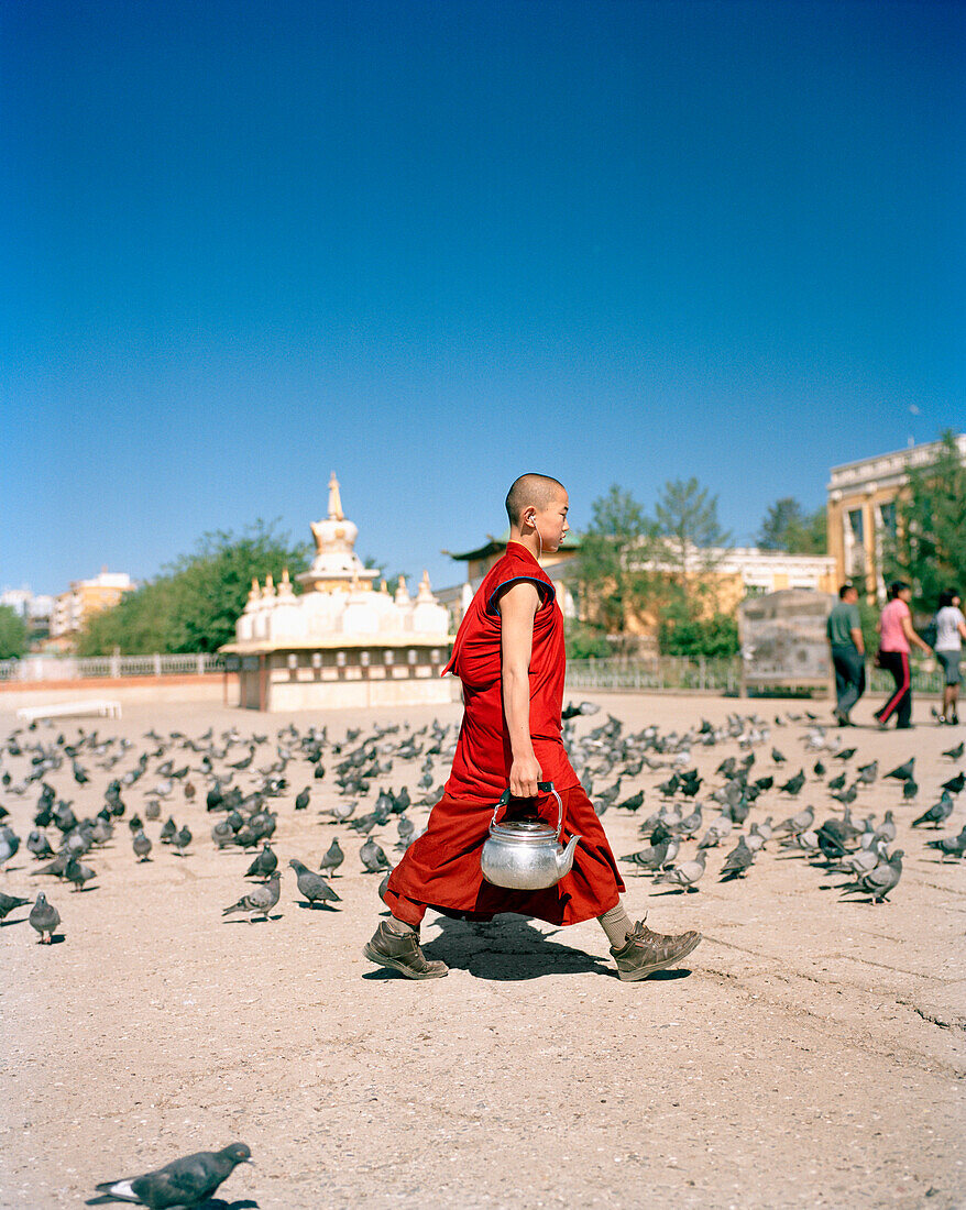 MONGOLIA, Ulaanbaatar, young monk walking with a pot of tea at the Gandan Monastery