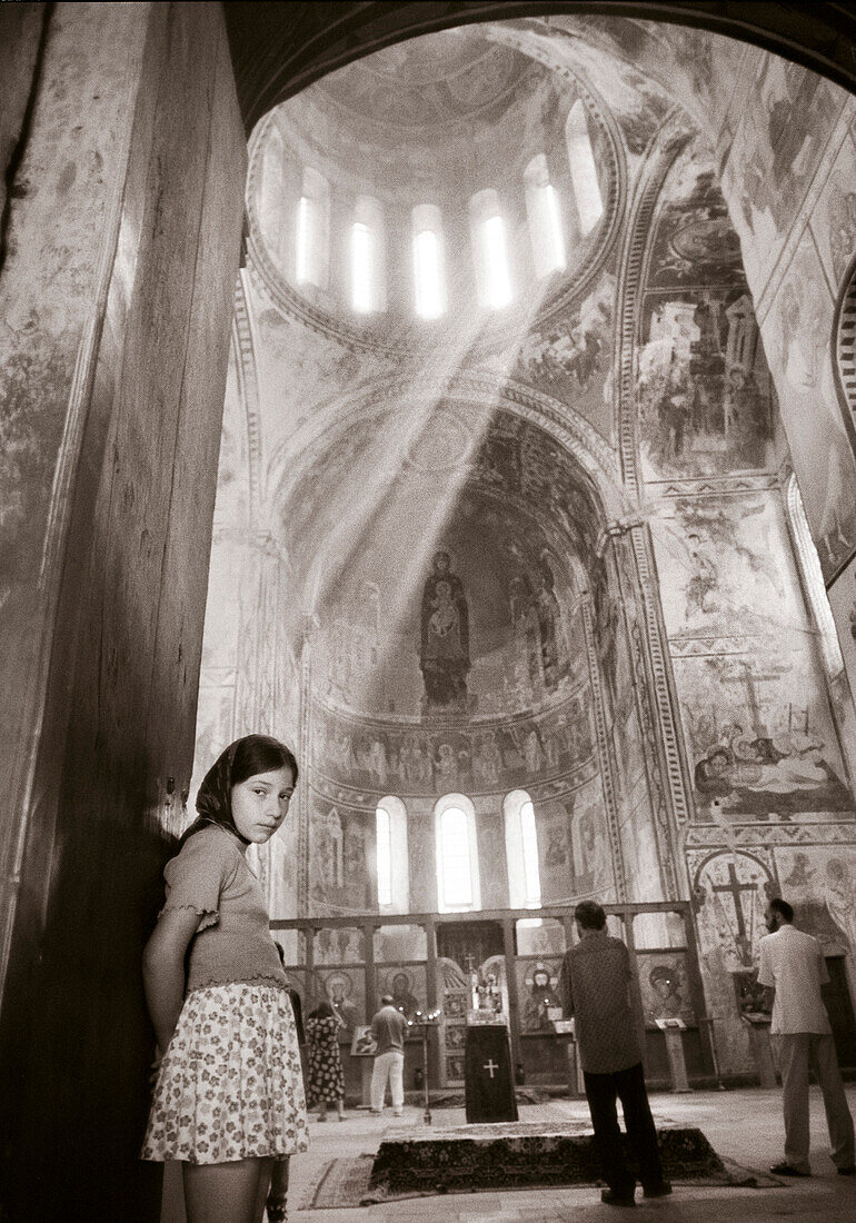 REPUBLIC OF GEORGIA, portrait of girl standing in entrance of a Russian Orthodox Church, Tbilisi (B&W)