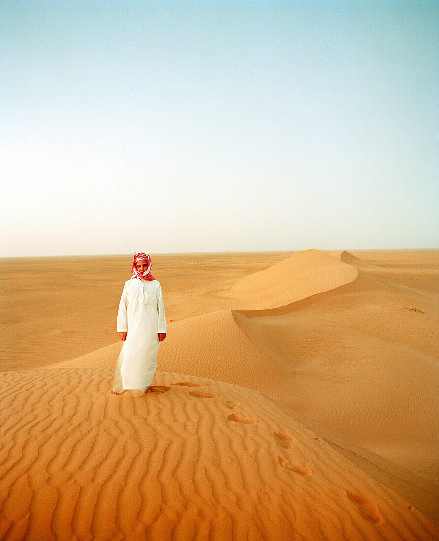 SAUDI ARABIA,The Empty Quarter, Najran, teenage boy standing on sand dune