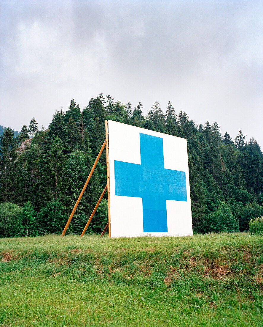 SWITZERLAND, Motiers, the symbol of the Swiss is displayed on the hillside above the town of Motiers, Jura Region