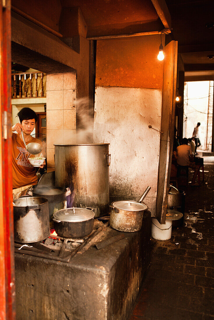 VIETNAM, Hanoi, restaurant Pho Gia Truyen, also known as 49 Bat Dan, a young boy serves pho broth into a bowl