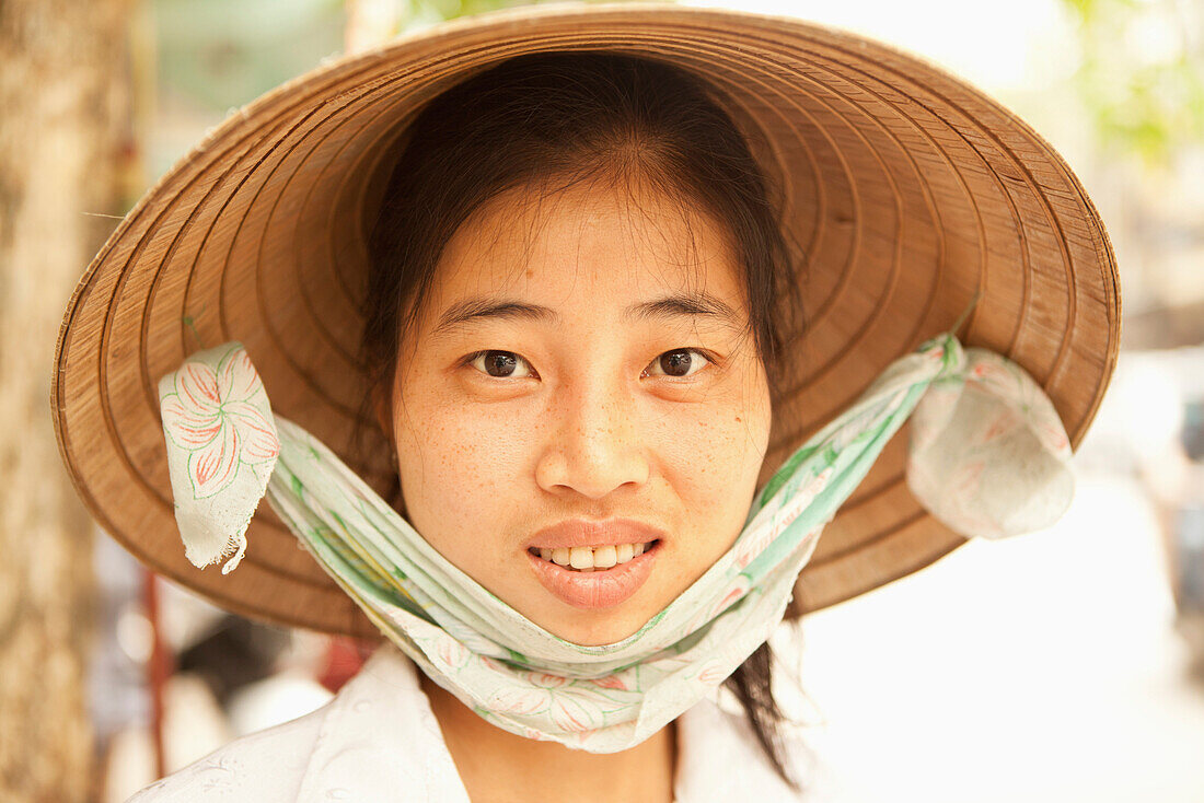 VIETNAM, Hanoi, portrait of a beautiful young woman selling produce and wears a non la or leaf hat, the old quarter of town