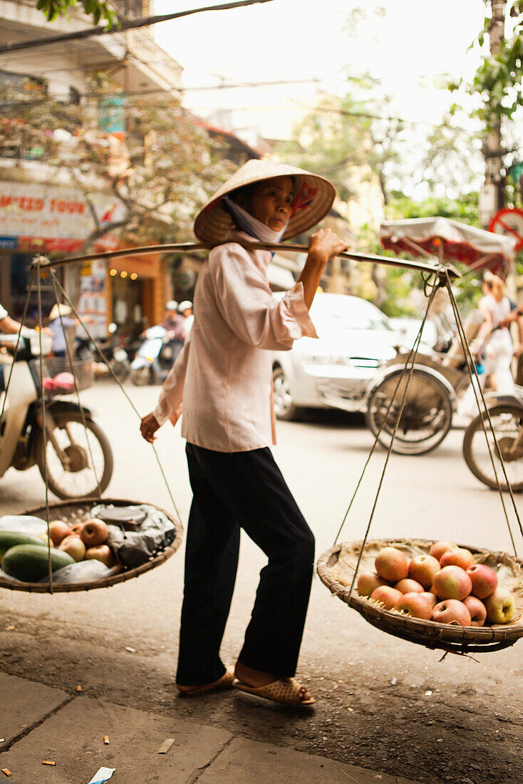 VIETNAM, Hanoi, a woman sells fruit on the street in front of Cafe Nang in the Old quarter
