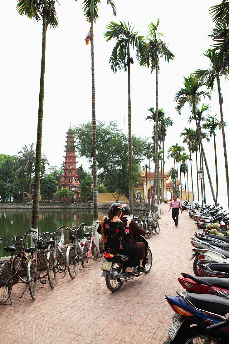 VIETNAM, Hanoi, two people on a moped look for a place to park, Tran Quoc Pagoda