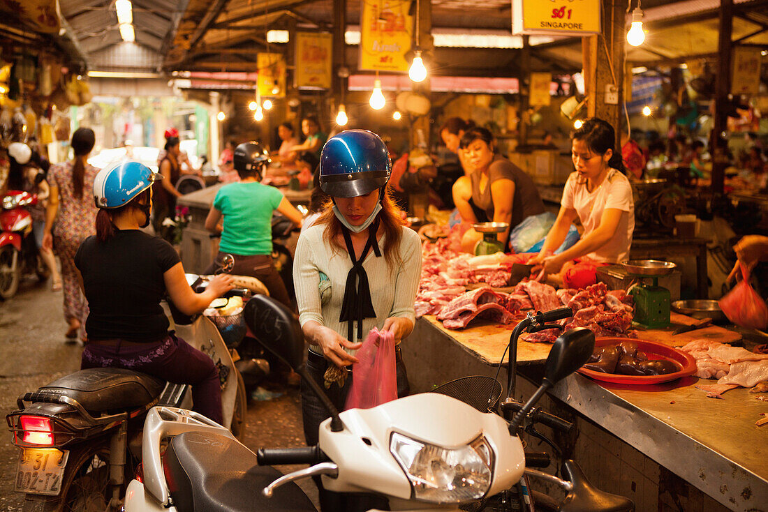 VIETNAM, Hanoi, a young woman buys meat from a butcher in the Chau Long Market