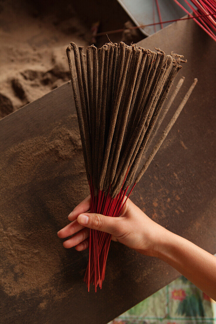 VIETNAM, Hue, a woman holds incense that she recently rolled and is selling on the roadside