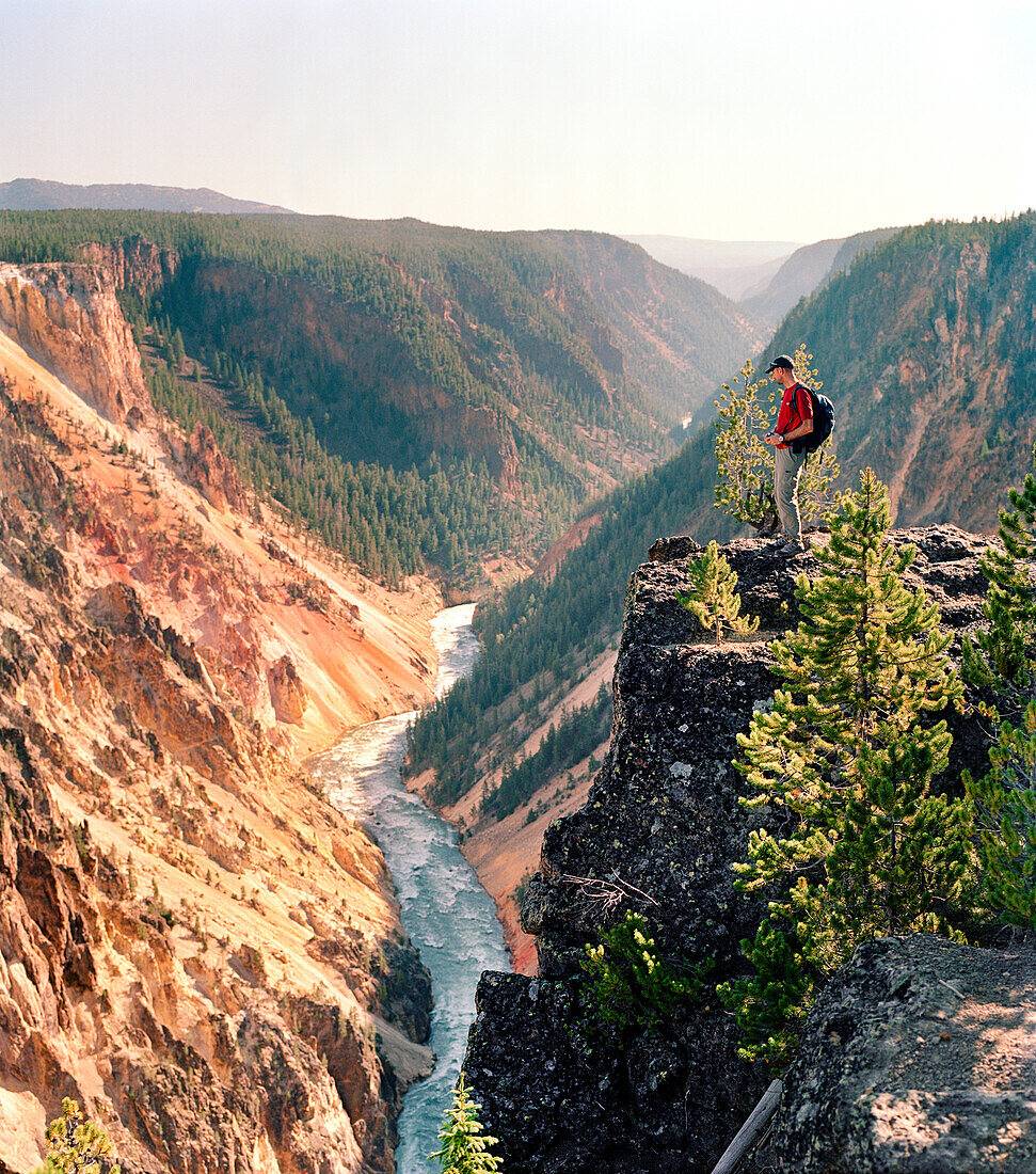 USA, Wyoming, man standing on cliff edge looking into Yellowstone Canyon, Yellowstone National Park