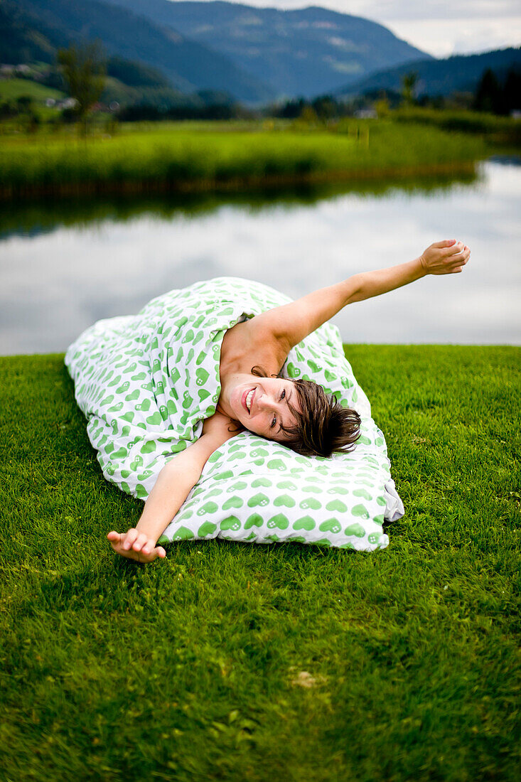 Woman lying with bedding on a golf course, Styria, Austria