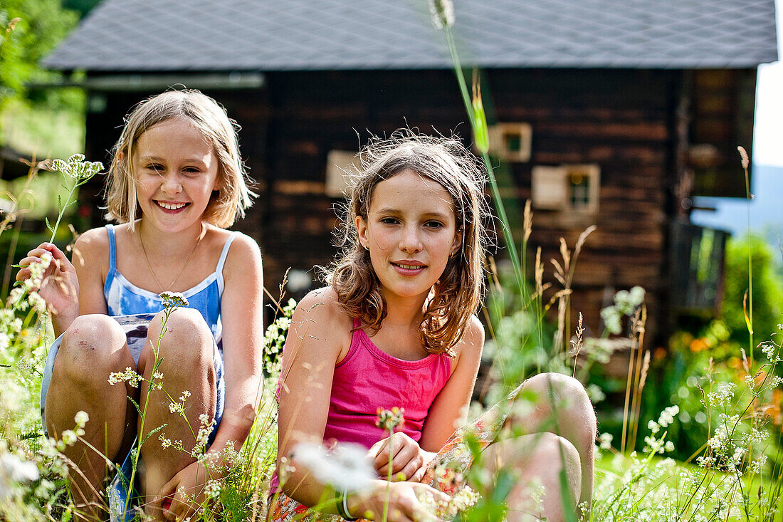 Two girls sitting in a meadow, Styria, Austria