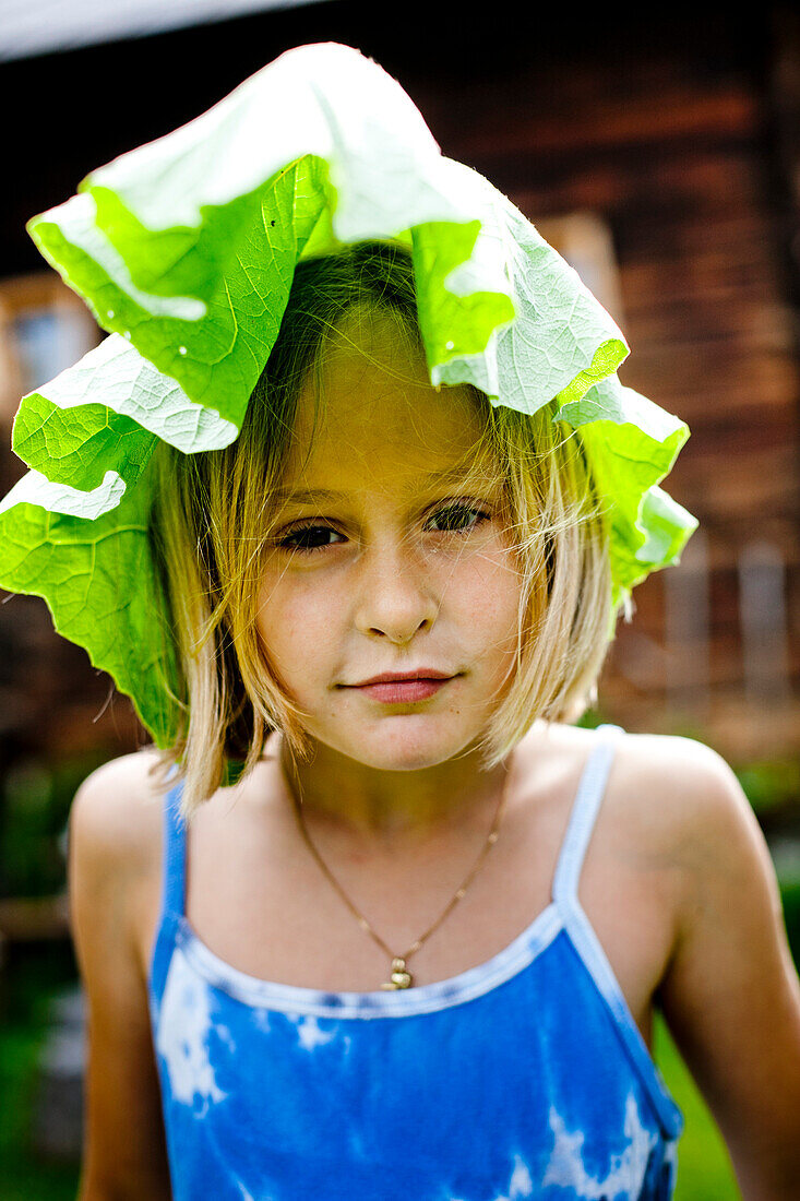 Girl covering head with a big leaf, Styria, Austria
