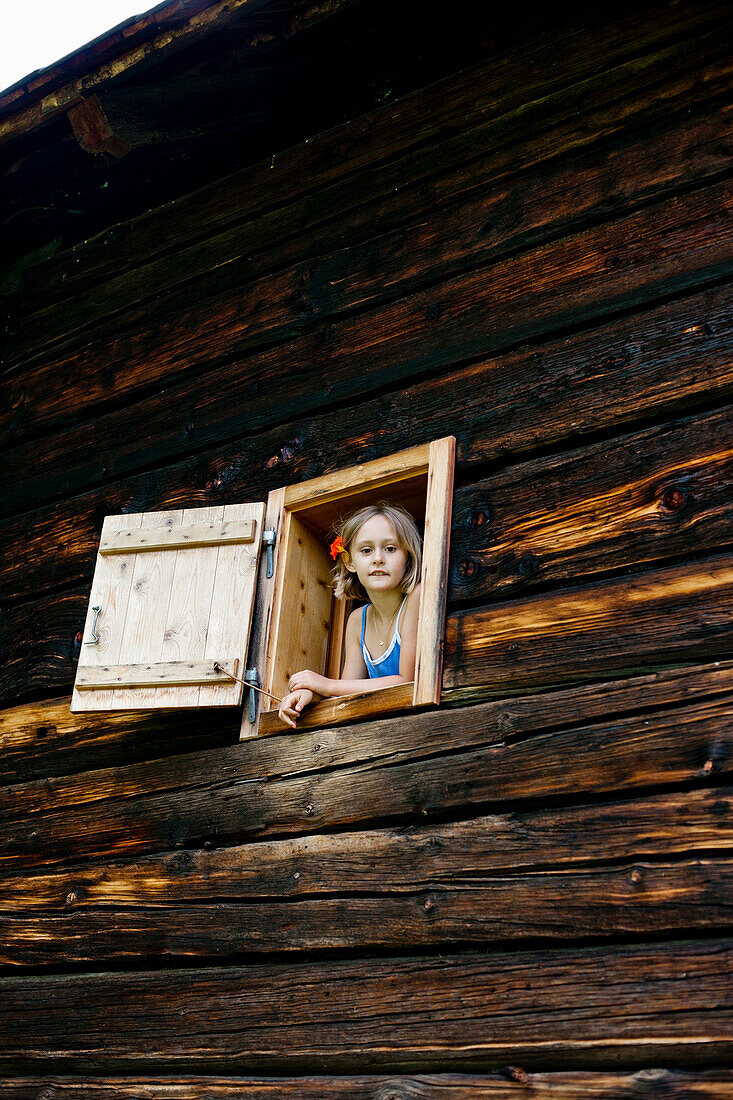Mädchen schaut aus dem Fenster von einem Bauernhaus, Steiermark, Österreich