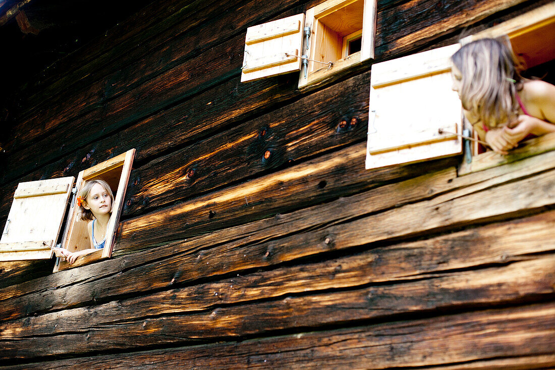 Zwei Mädchen schauen aus einem Bauernhaus, Steiermark, Österreich