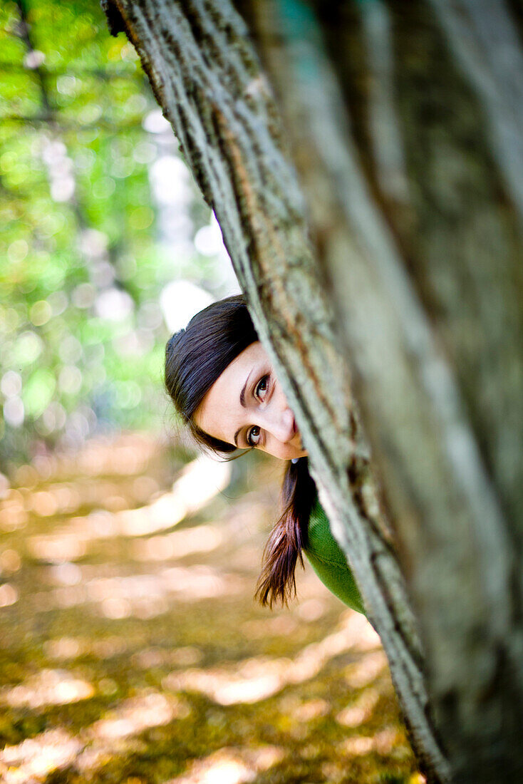 Young woman behind a tree, Styria, Austria